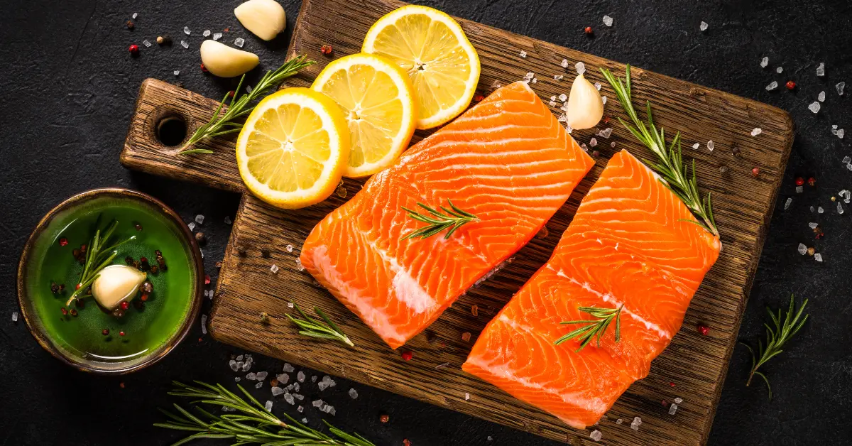 Elintarviketurvallinen lohi puisella leikkuulaudalla rosmariinin ja sitruunan kera