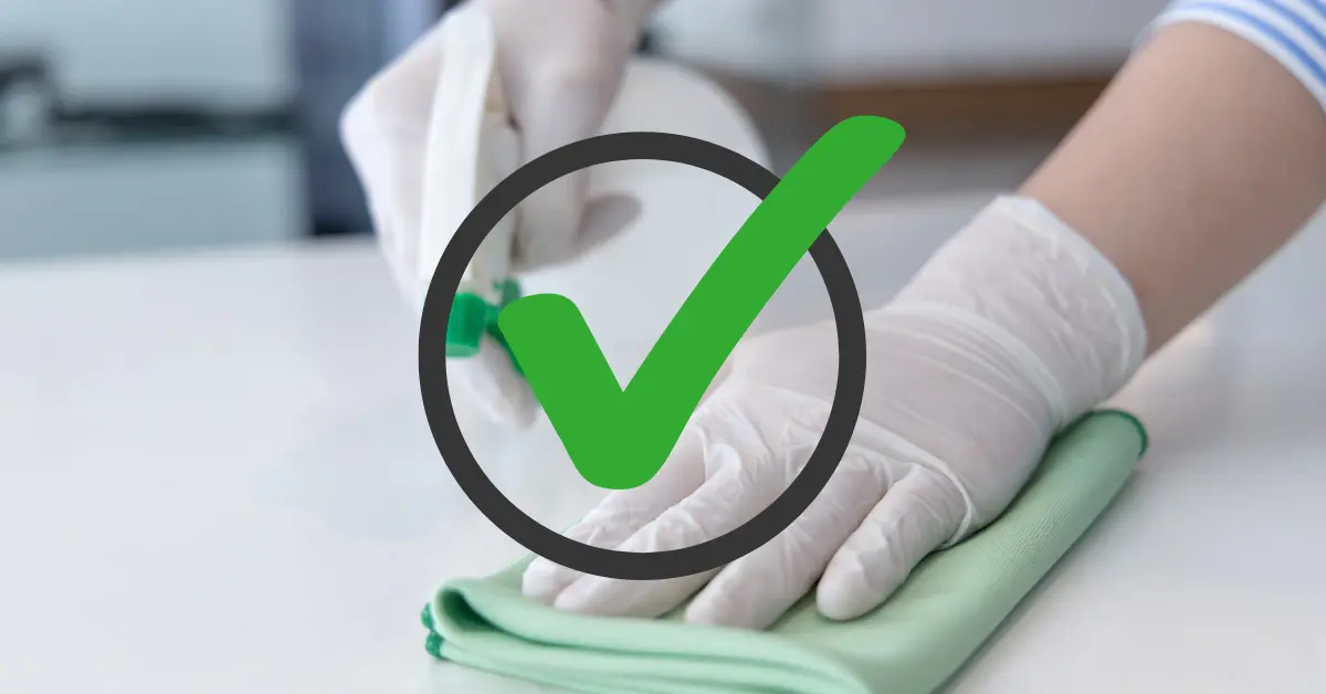 Kaksi kättä, joissa toisessa on puhdistusliina ja toisessa suihkepullo. Kuvan päällä "done" -merkki kuvaamassa sitä, että puhdistus on tehty oikein.